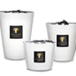 Three Baobab Collection Les Prestigieuses Pierre De Lune Candles in white vessels of varying sizes, each displaying a Baobab logo and a black ribbon on the lid.
