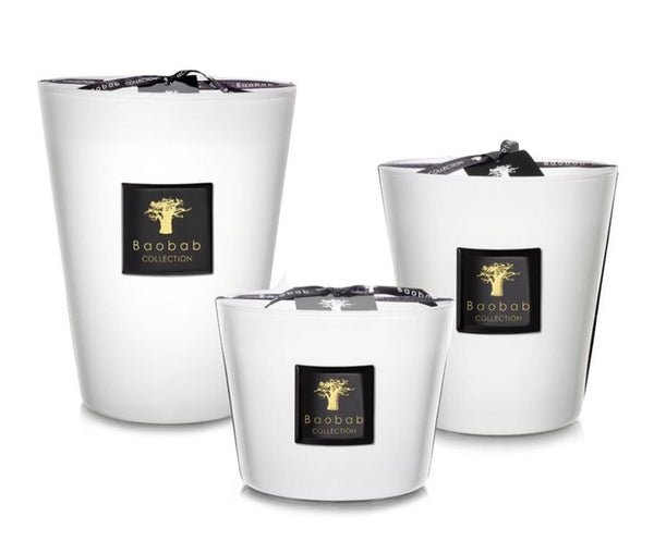 Three Baobab Collection Les Prestigieuses Pierre De Lune Candles in white vessels of varying sizes, each displaying a Baobab logo and a black ribbon on the lid.