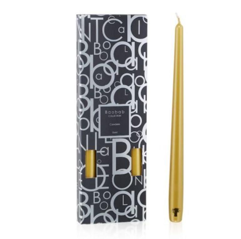 A Baobab Collection Candela Candlestick in gold stands gracefully next to a black patterned box labeled with the "Baobab" brand, its sheen shimmering in the light. Perfect for any candlestick holder, it offers a long-lasting burn that elevates any occasion.