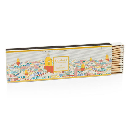 A rectangular box from the Baobab Collection Saint Tropez Body Wellness Collection, partially open and featuring a colorful town illustration, captures the summer-inspired freshness of this Baobab wellness line.