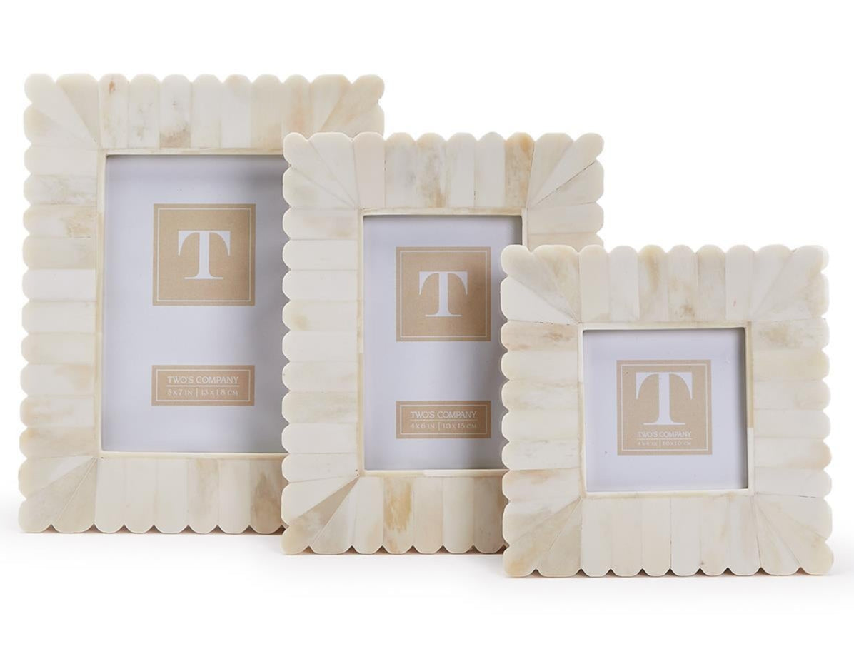 The Bone Scalloped Frame Collection by Two's Company features three cream-colored decorative frames with scalloped edges, displayed upright side by side against a plain white background.