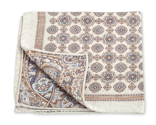 A reversible R. Hanauer Medallion Paisley Pocket Square made in Italy, featuring an intricate floral and paisley pattern in beige, blue, and brown colors. The design is symmetrical and detailed.