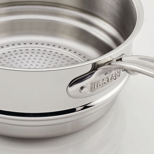 Close-up of the Hestan Provisions Stainless Steel Steamer Insert, 3qt, featuring a shiny triple-bonded construction, perforated design for steaming, and a handle engraved with "Hestan.