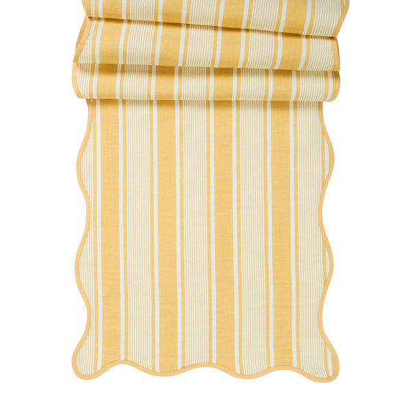 The Juliska Cabana Stripe Tabletop Collection features yellow and white cabana striped fabric with scalloped trim, partially folded at the top.