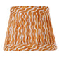 The Zafferano x Fermoie Poldina Lampshade Collection by Zafferano America features a hand-made orange and white wavy striped lampshade on a white lamp stand, shown against a plain white background.