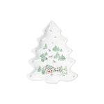 The Juliska Berry & Thread North Pole Tree Platter Collection features a white ceramic platter shaped like a Christmas tree, adorned with a winter village scene of trees, houses, and reindeer in green, red, and blue.