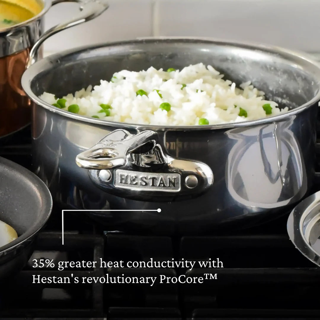 A Hestan NanoBond Covered Saucepan with cooked rice and peas sits on a stovetop. Its wider base ensures even heating and delivers 35% greater heat conductivity thanks to Hestan’s revolutionary ProCore™.