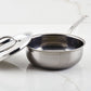 A Hestan NanoBond Titanium Stainless Steel Saucier Pan, 2qt, with its lid beside it rests on a white marble surface; it's designed to be safe for use with metal utensils.