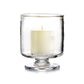 A white pillar candle sits inside a clear, stemmed Simon Pearce Nantucket Hurricane Collection holder against a white background.