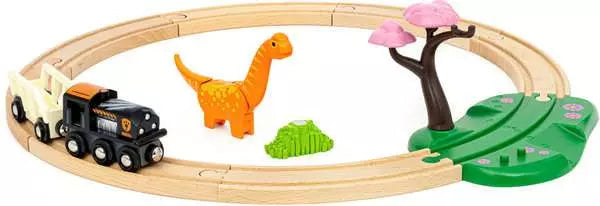 The BRIO World Dinosaur Circle Set by Brio includes a wooden dinosaur-themed train set that features an oval track with a black engine, an orange dinosaur figurine, a green bush, and a pink and green tree.