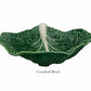 The HIVE Cabbage Leaf Green Collection features a green ceramic handmade bowl with an uneven, wavy rim and white central ridge—an artistic addition to your serveware. "Crooked Bowl" is labeled below the image.