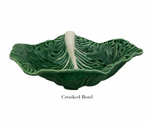 The HIVE Cabbage Leaf Green Collection features a green ceramic handmade bowl with an uneven, wavy rim and white central ridge—an artistic addition to your serveware. "Crooked Bowl" is labeled below the image.