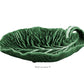 A green ceramic handmade dish from HIVE’s Cabbage Leaf Green Collection, shaped like a leaf with curled stem handle and visible veins, labeled “With Curvature 9°.” Part of our Serveware Collection.