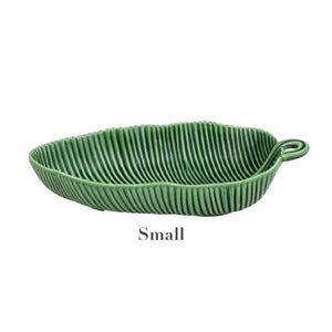 A small, green, leaf-shaped ceramic dish with a ribbed texture and handle. Handmade by HIVE, this piece from the Banana Leaves Salad Bowl Collection brings charm to any table setting.