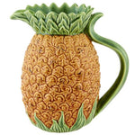 The Hive Pineapple Pitcher is a ceramic pitcher shaped and textured like a pineapple, featuring green leaves that form the top and handle.