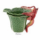 The HIVE Cabbage with Lobsters Serveware Collection features a handmade ceramic pitcher shaped like a green cabbage leaf with a red lobster handle, labeled "Pitcher" and shown on a white background. A unique serveware accent.