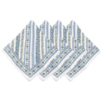 Four patterned napkins from Juliska's Seville Green Stripe Table Linen Collection, featuring blue and green floral and stripe designs, are fan-arranged on white—perfectly complementing any cork-backed placemat for an elegant table setting.