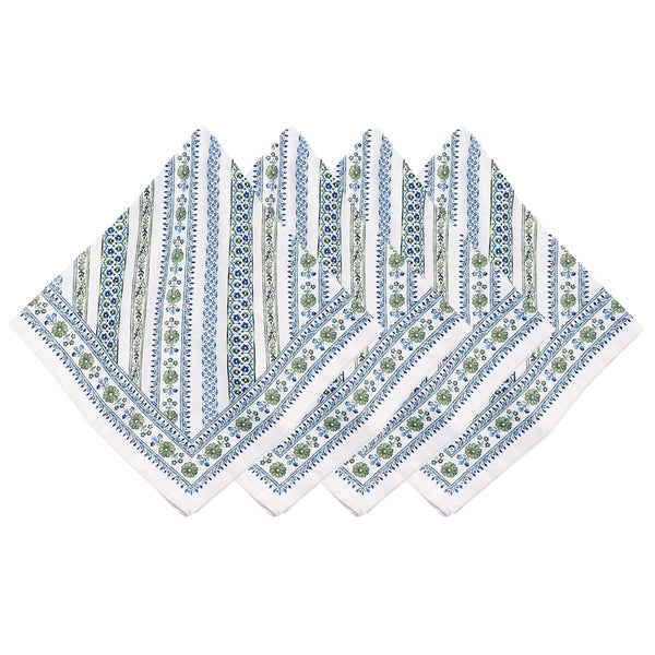 Four patterned napkins from Juliska's Seville Green Stripe Table Linen Collection, featuring blue and green floral and stripe designs, are fan-arranged on white—perfectly complementing any cork-backed placemat for an elegant table setting.