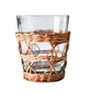 The Seagrass Rattan Cage Tumbler Collection by Be Home features clear glass tumblers with woven rattan sleeves, adding rustic charm to your table against a white backdrop.