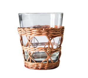 The Seagrass Rattan Cage Tumbler Collection by Be Home features clear glass tumblers with woven rattan sleeves, adding rustic charm to your table against a white backdrop.