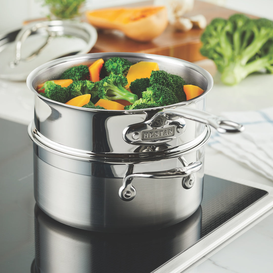 The Hestan Provisions Stainless Steel Steamer Insert, 3qt, holds broccoli and sliced yellow bell peppers as it rests on an electric stovetop.