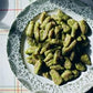 A decorative plate filled with green gnocchi, inspired by the recipes in *Pasta Grannies: Comfort Cooking* from Chronicle Books, sits on a white tablecloth with a faint plaid pattern.