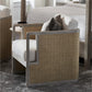 The PALECEK Aveline Lounge Chair features a hardwood frame, beige woven sides, and white cushions, shown on a patterned rug beside a bed with neutral bedding.