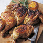 Quartered roast chicken arranged on a wooden board, accompanied by grilled lemon halves and fresh rosemary sprigs—a simple yet flavorful home-cooked meal inspired by *Barefoot Contessa Back To Basics* from Penguin Random House.
