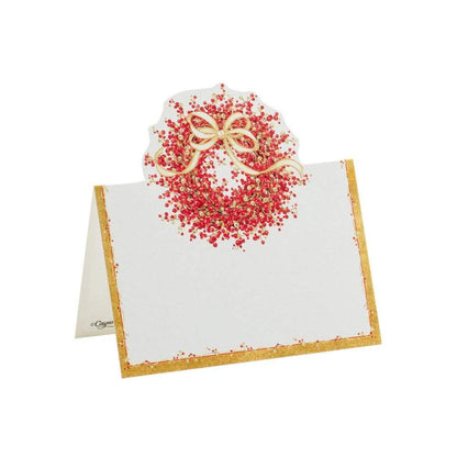 A white place card from Caspari’s Pepperberry Tabletop and Stationery Collection features a gold border and red berry wreath with a gold bow, ideal for pairing with matching luncheon or cocktail napkins at your festive table.