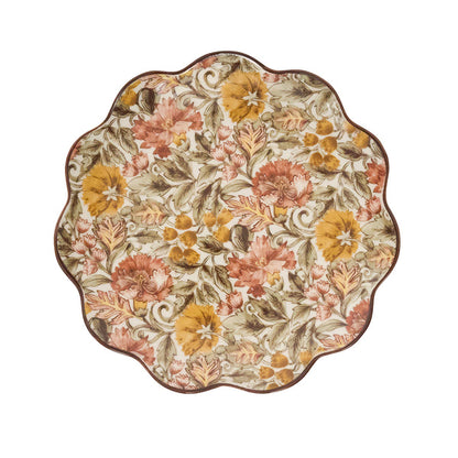 The Willa Dinnerware Collection by Juliska features a round scalloped charger with dense romantic florals in yellow, pink, and green plus a brown rim—perfect as a charming serving platter.