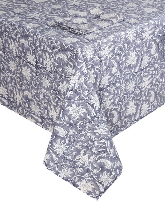 The Madrid Table Linen Collection by SLOANE BY HAND features a blue and white hand block printed rectangular tablecloth with a matching artisanal napkin, neatly folded on top for a cohesive look.