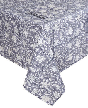 The Madrid Table Linen Collection by SLOANE BY HAND features a blue and white hand block printed rectangular tablecloth with a matching artisanal napkin, neatly folded on top for a cohesive look.