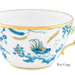 White porcelain tea cup from Ginori 1735's Oro Di Doccia Turchese Dinnerware Collection, featuring blue floral and Ji Ondori rooster designs with a hand-painted gold rim and handle, labeled "Tea Cup" on the bottom right.