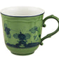 The Oriente Italiano Malachite Mug by Ginori 1735 showcases a green ceramic finish with a dark blue floral motif and scalloped handle, inspired by Faenza ceramics, displayed on a white background.