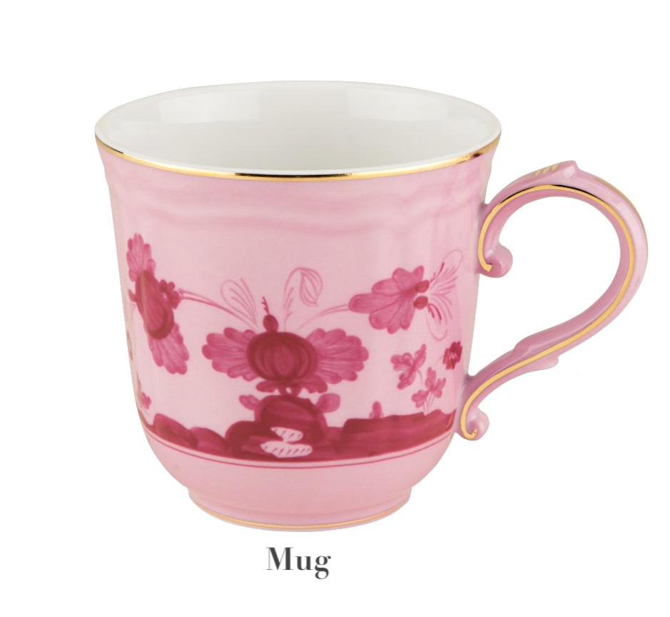 A pink ceramic mug with floral patterns, gold rim, and curved handle showcases Italian elegance by Ginori 1735 as part of the Oriente Italiano Porpora Dinnerware Collection. "Mug" is labeled below the image.