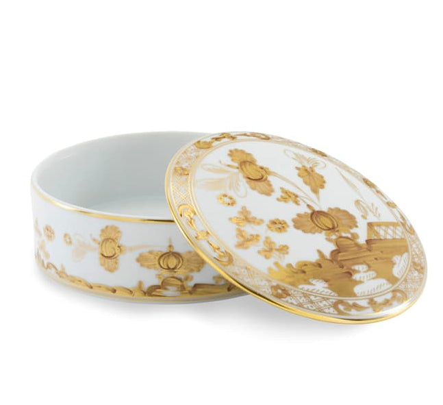 The Oriente Italiano Aurum Decor Collection by Ginori 1735 features a round porcelain box with a removable lid, adorned with gold patterns and floral motifs on white—an elegant home decor piece.