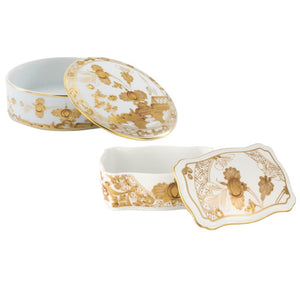Two porcelain boxes from the Ginori 1735 Oriente Italiano Aurum Decor Collection—one round, one rectangular—feature gold floral designs and are shown with their lids partially open.