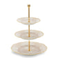 The Ginori 1735 Oriente Italiano Meringa Collection features a three-tiered serving stand with gold support and three round, scalloped-edge porcelain plates in an elegant pattern.