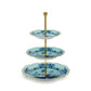 A three-tiered serving stand from Ginori 1735's Oriente Italiano Iris with Gold Dinnerware & Decor Collection, featuring blue and white patterned plates inspired by porcelain dinnerware and a gold metal frame.