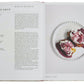 An open copy of *Classic French Recipes* by Phaidon features a recipe for eggs in Meurette sauce on the left page and a plated dish of the recipe on the right, capturing the essence of French home cooking.