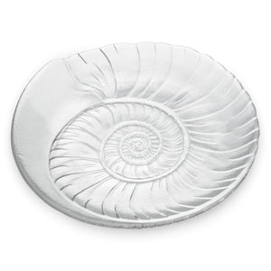 The Shell Serveware Collection by Simon Pearce features a round, clear glass plate with an embossed spiral shell design—an ideal accent for beach-themed decor or a standout summer host gift.