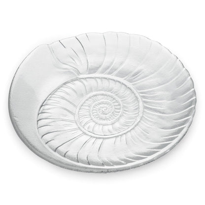 The Shell Serveware Collection by Simon Pearce features a round, clear glass plate with an embossed spiral shell design—an ideal accent for beach-themed decor or a standout summer host gift.