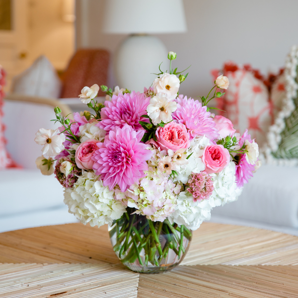 A Hive Floral Studio Live Designer's Choice floral arrangement of pink and white flowers sits on a table in the living room.