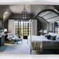 A modern bedroom inspired by Ray Booth: The Expressive Home from Rizzoli features a spacious bed, cozy fireplace, elegant lounge chair, and expansive floor-to-ceiling windows that invite abundant natural light. Decorated in neutral tones with contemporary furnishings, the space achieves a timeless aesthetic ideal for sophisticated homes.