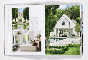 An open copy of *Ray Booth, The Expressive Home* by Rizzoli displays images of sophisticated homes, featuring a modern white house, landscaped garden, pool, and a bright bedroom with large windows and elegant decor.