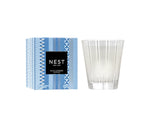 A Blue Cypress & Snow Collection candle from Nest is displayed beside its blue-patterned box, showcasing the winter scent by Nest.