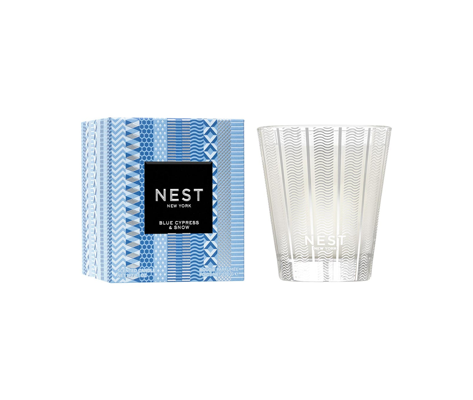 A Blue Cypress & Snow Collection candle from Nest is displayed beside its blue-patterned box, showcasing the winter scent by Nest.