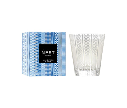 A Blue Cypress & Snow Collection candle from Nest is displayed beside its blue-patterned box, showcasing the winter scent by Nest.