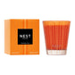 A Nest Pumpkin Chai Candle from the Pumpkin Chai Candle Collection sits by its matching box, both with geometric designs and black labels—ideal for creating a cozy autumn ambiance.