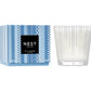 A Nest Blue Cypress & Snow Collection candle in a patterned blue box (left) and clear textured glass holder (right), offering a winter scent with smoked vanilla bean notes.